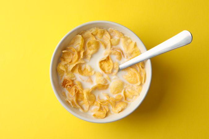 Bowl with muesli and milk on yellow background