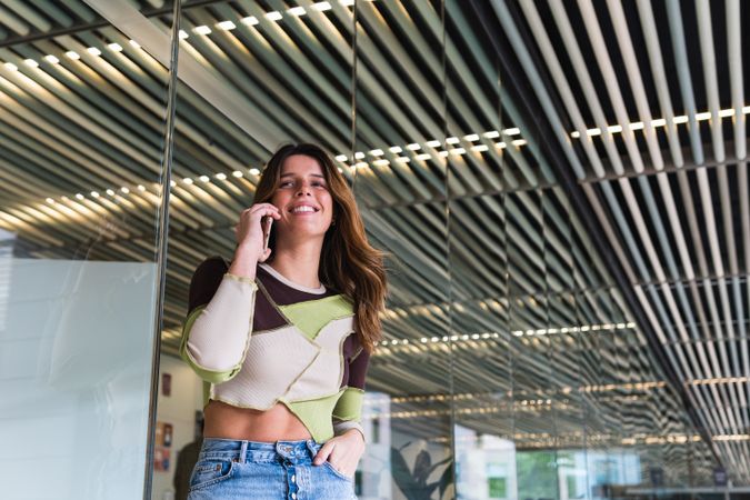 Cheerful woman speaking on smartphone in modern building