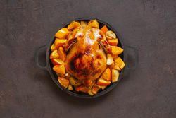 Chicken pot cooked with oranges on dark brown table