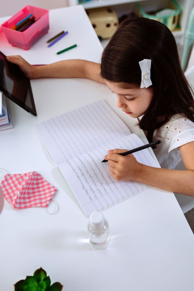 Girl studying at home with mask and sanitizer gel