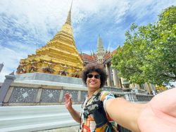 Tourist takes a selfie with a beaming smile in a historic golden temple in Asia.