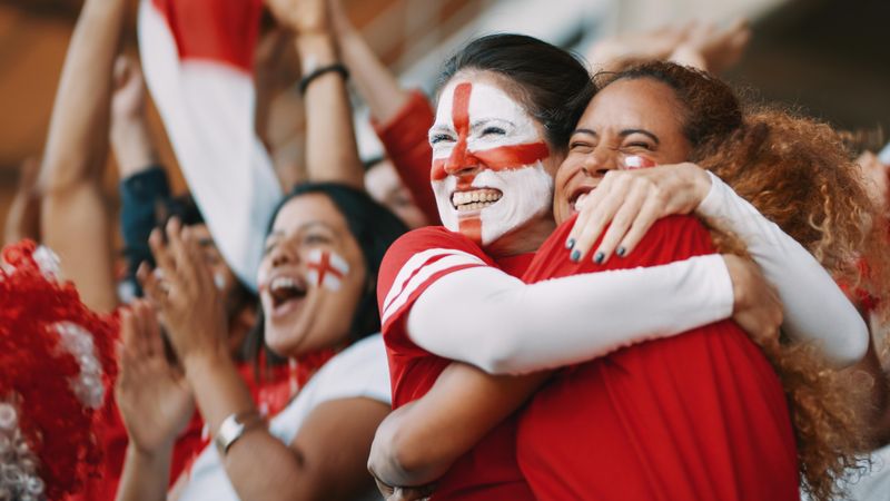 English female spectators in football stadium celebrating their team's victory