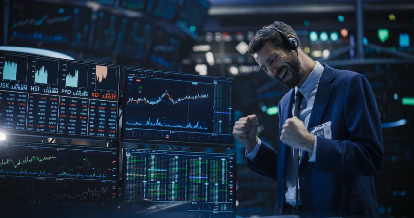 Professional Broker Hears the Good News on a Call in His Headset, Punches the Air in a Winning Fashion, Showing Positive Emotions