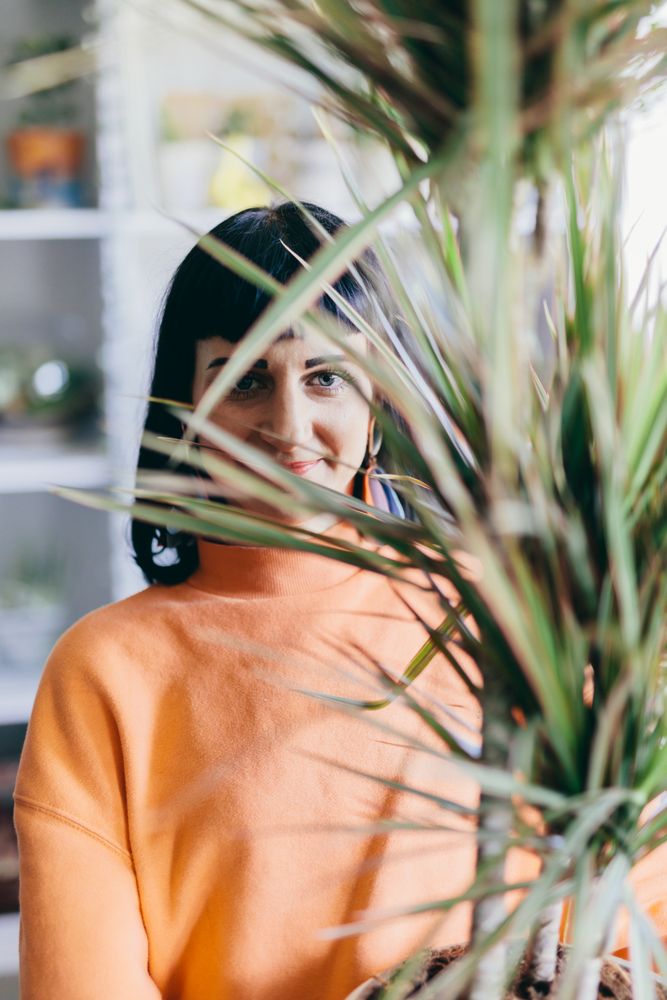 Woman's face behind leaves of big plant.