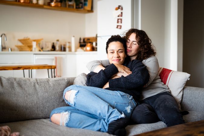 Happy female couple holding each other on sofa