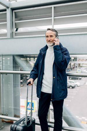 Older man on the phone outside airport