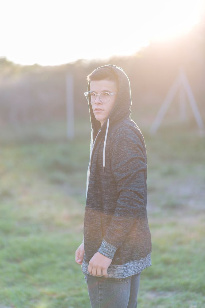 Teenage male in hoodie standing in field