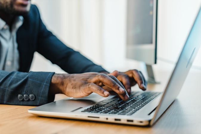 Crop Black businessman typing on laptop