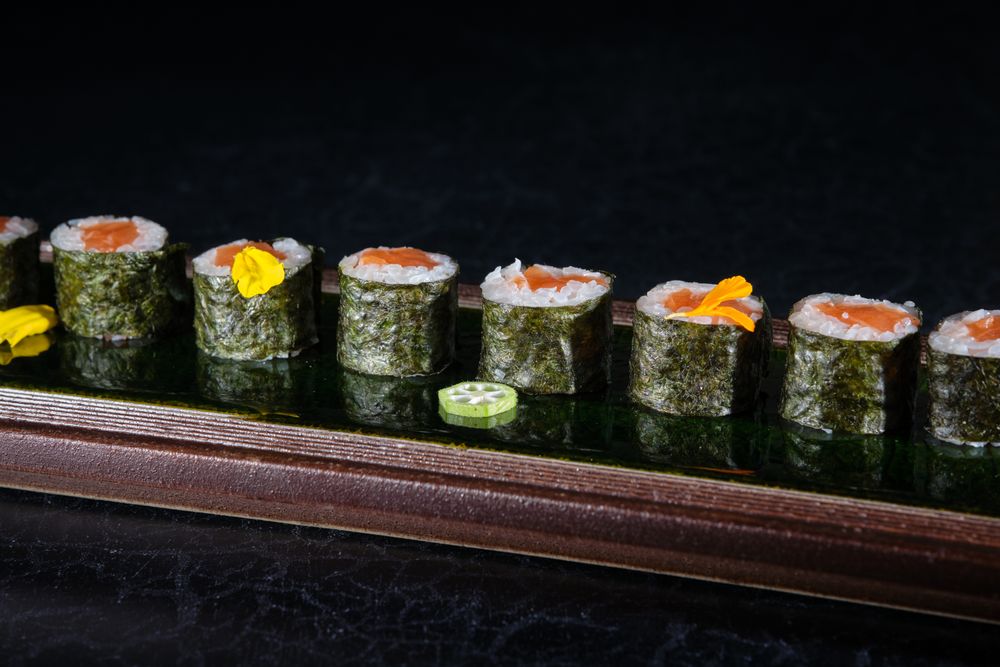 Appetizing sushi rolls with salmon and pepper on tray