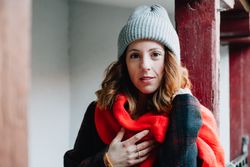 Positive woman in warm wear near house