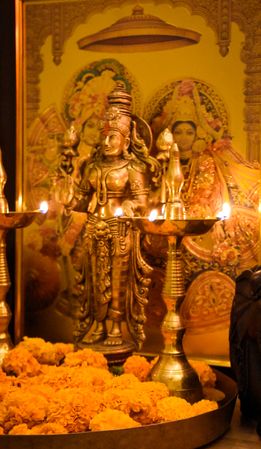 Side view of Lakshmi figurine between two Diyas on marigold flowers