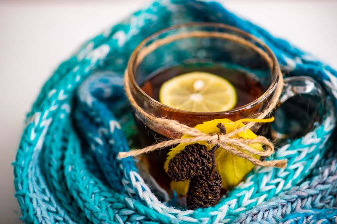Autumnal tea with lemon decorated with pine cones wrapped in blue scarf