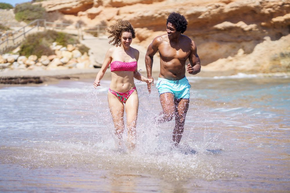 Interracial couple walking in water at beach
