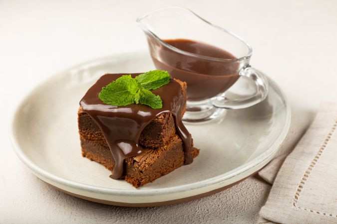 Brownies served with pot of chocolate sauce and mint garnish
