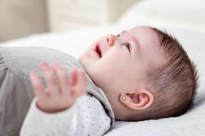 Baby girl crying over white bedcover