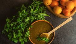 Bowl of plums and fresh parsley with Georgian Tkemali Sauce