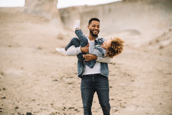 Black father playing with child on ground