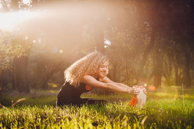 Happy woman stretching on sunny meadow