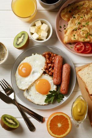 Vertical shot of full breakfast with eggs, beans, sausage, fruit and orange juice