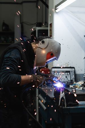 Anonymous mechanic welding metal construction in workshop