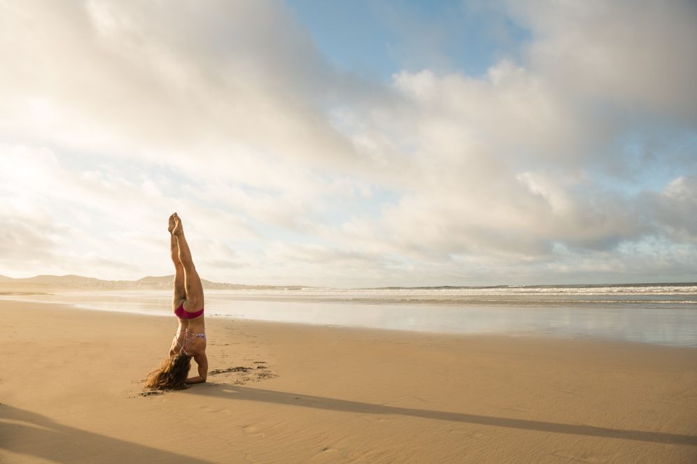 Woman doing handstand near sea