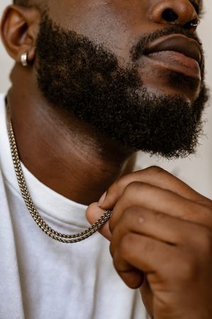 Cropped image of Black man with a beard wearing light shirt and silver necklace