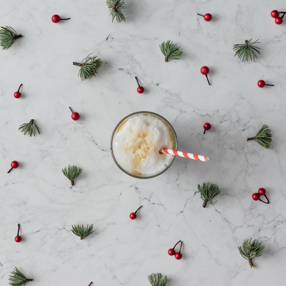 Holly and pine pattern on marble background with coffee