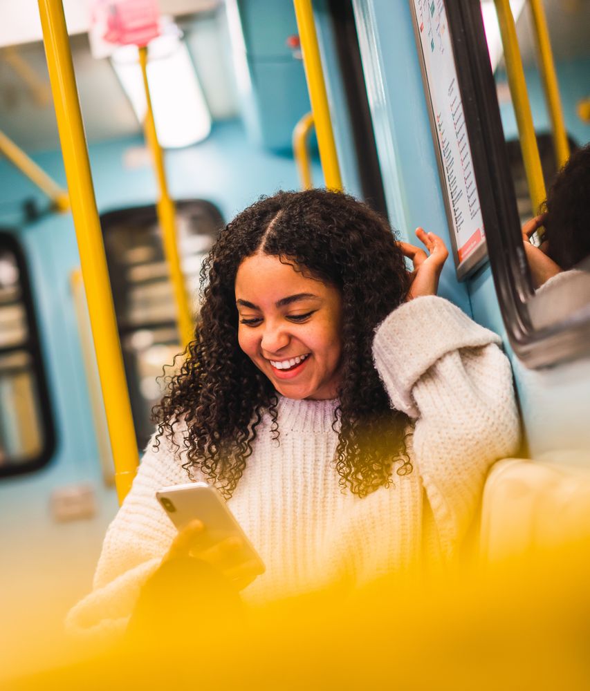 Smiling Black woman using smartphone in transport