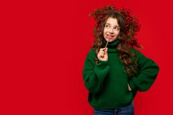 Young girl in a green sweater biting a candy cane