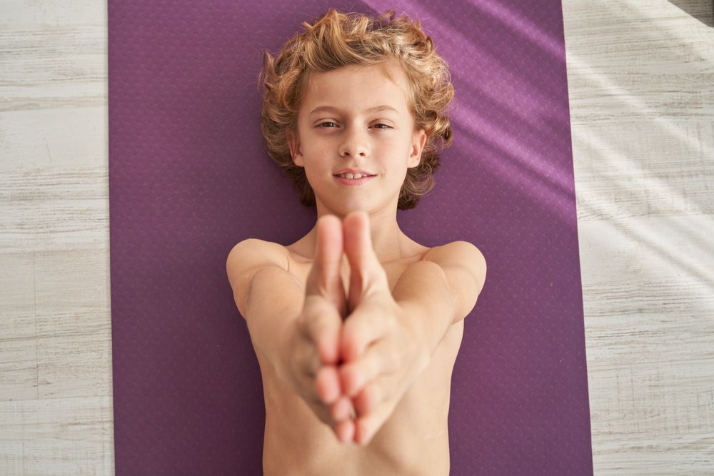 Content child with raised arms during yoga training