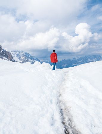 Unrecognizable lonely traveler walking on snowy hill