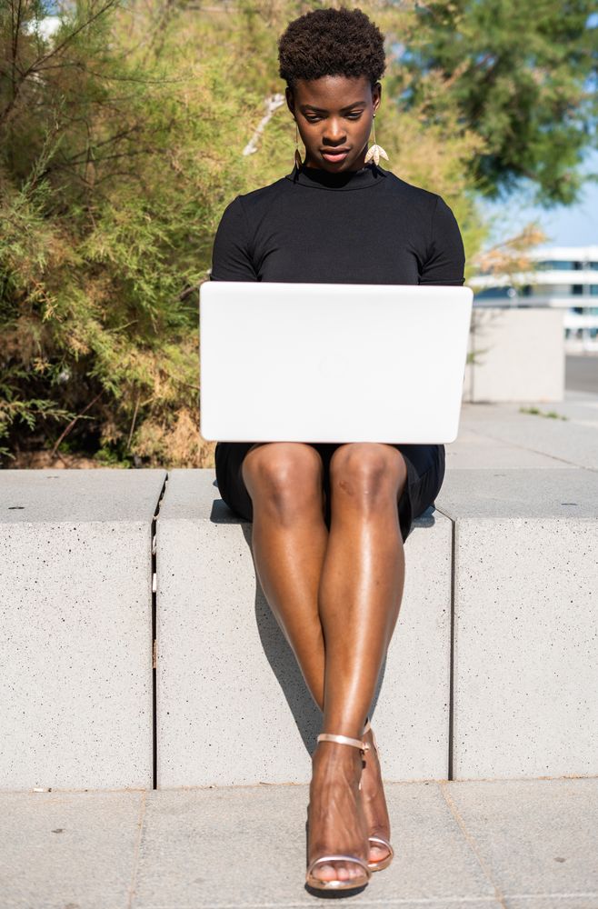 Serious female surfing laptop near modern building