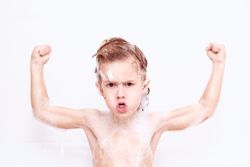 Boy showing strength in bathroom