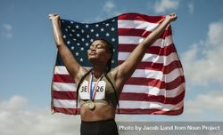 Female athlete with medal holding American flag with her eyes closed 4Mo2q0