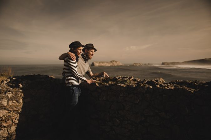 Man holding woman on hands near stones on shore