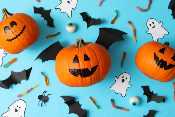 Halloween concept with pumpkins, ghosts, candies and bats on blue background