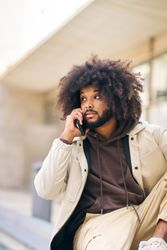Young man with curly afro hair on the street talking on the cell phone
