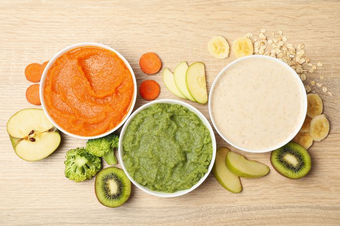 Bowls with vegetable puree on wooden background. Baby food