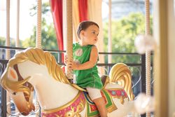 Curious little kid on colorful moving carousel at fair