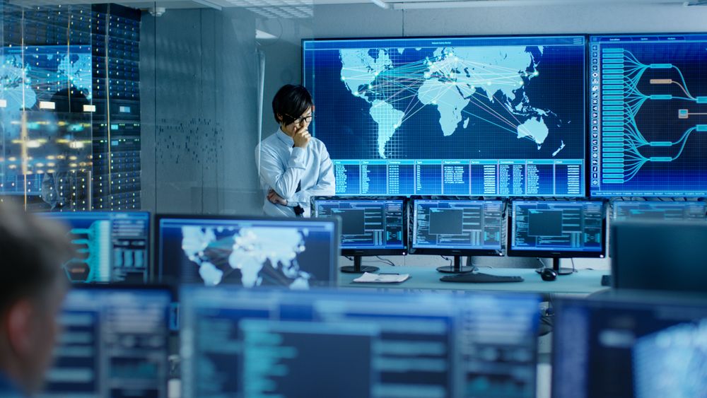 In the System Control Room Chief Engineer Thinks While Standing Before Big Screen with Interactive Map on it.