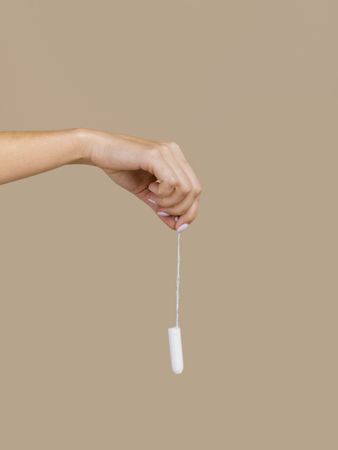 Hand holding tampon front view