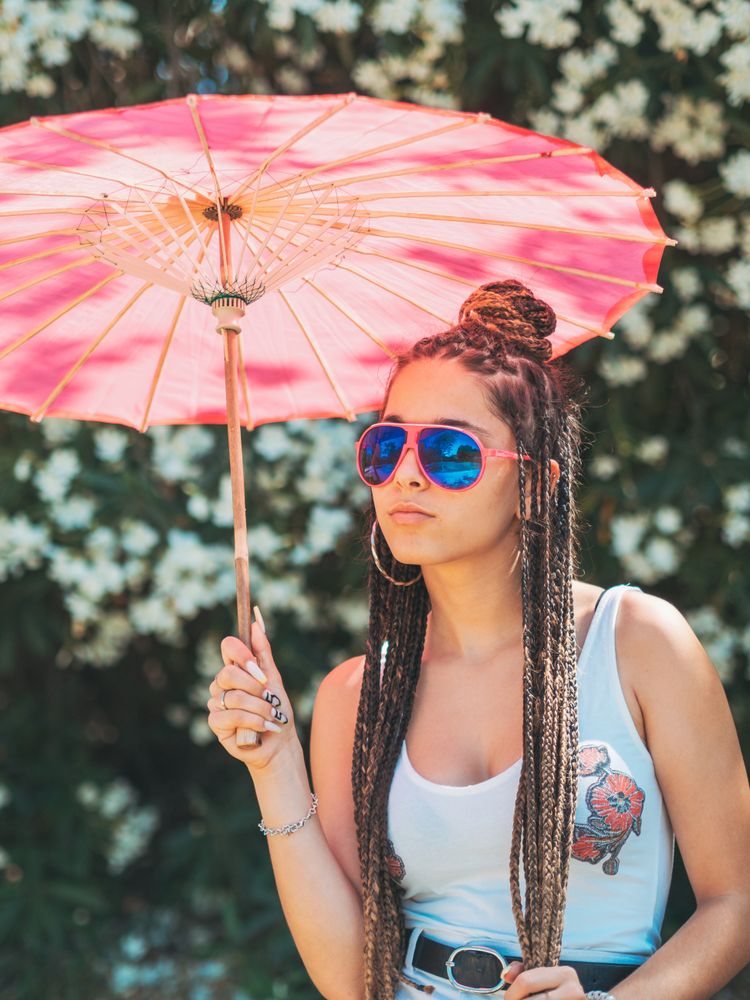Fit young female with umbrella standing near blooming trees