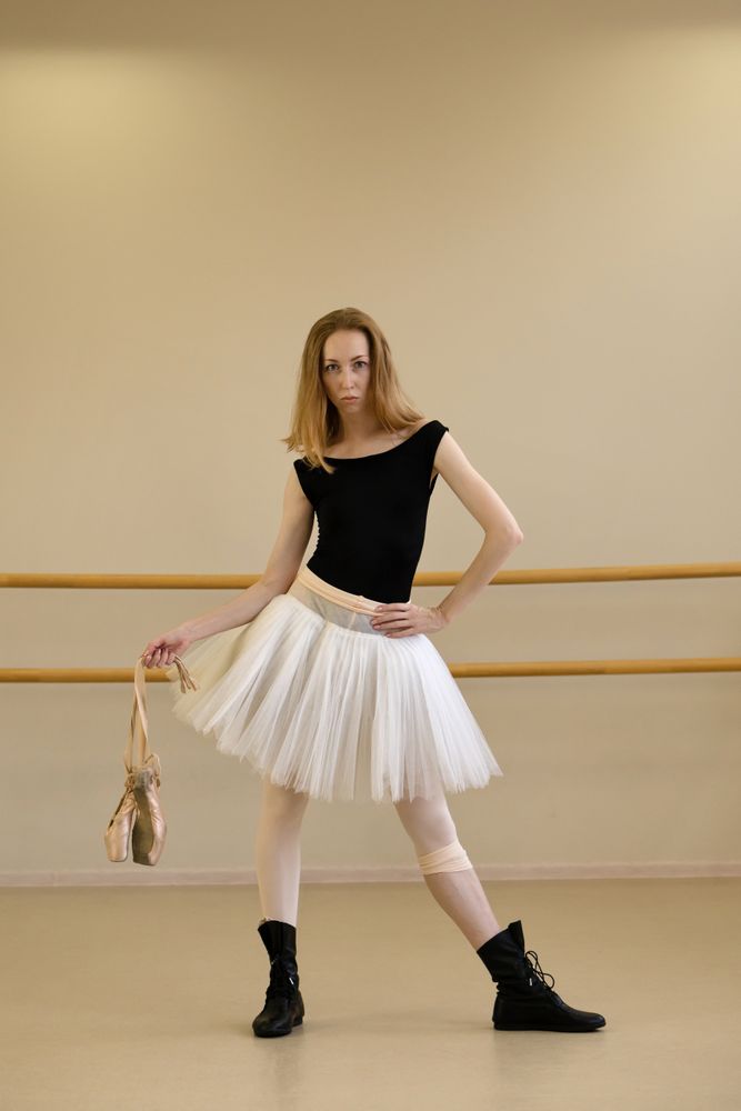 Ballerina posing with pointe shoes in hand