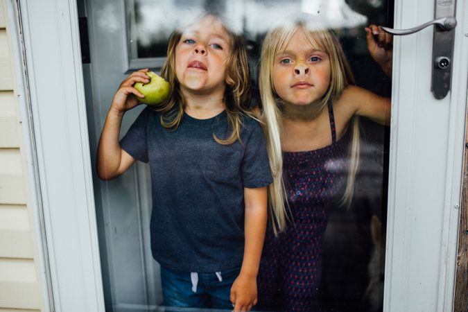 Two young girls pressing their nose against glass door