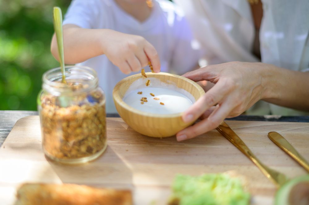 Unrecognizable kid preparing yogurt with granola