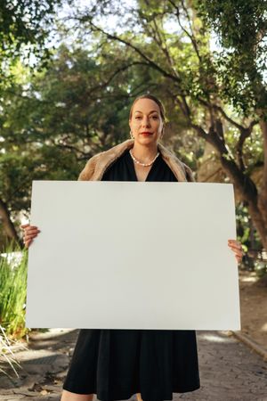 Confident posh woman looking at the camera while holding up a white placard