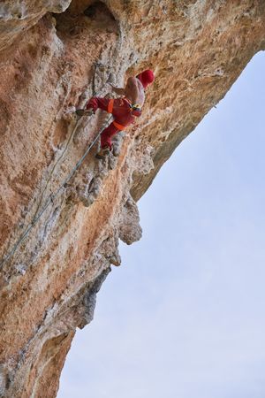 Anonymous strong man climbing on rock in mountains
