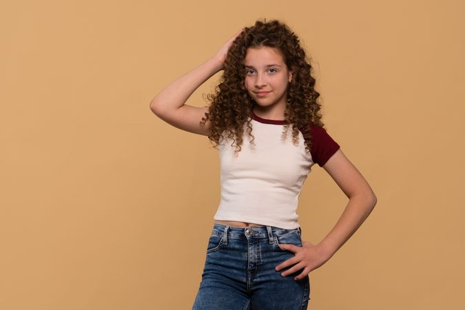 Young girl posing with hand on head, smiling confidently