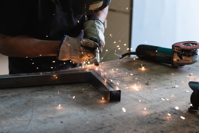 Crop master welding metal pieces at workbench