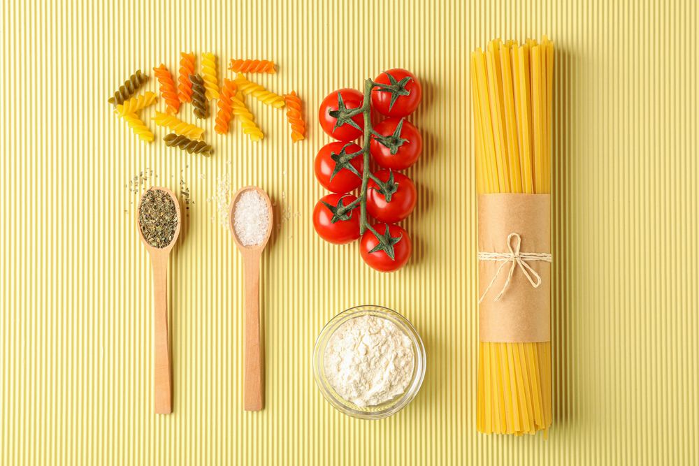 Flat lay composition with pasta ingredients on light background, space for text